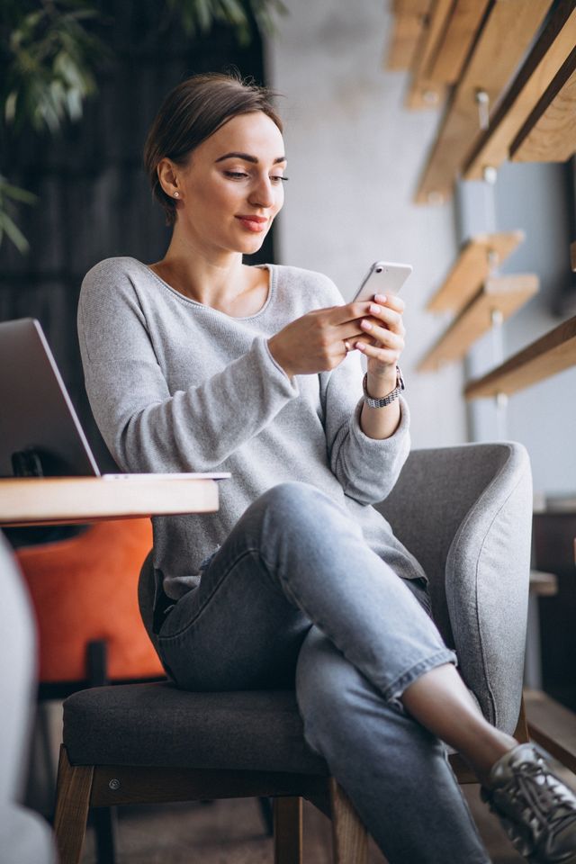 Una mujer revisa su celular, tranquila, en un café